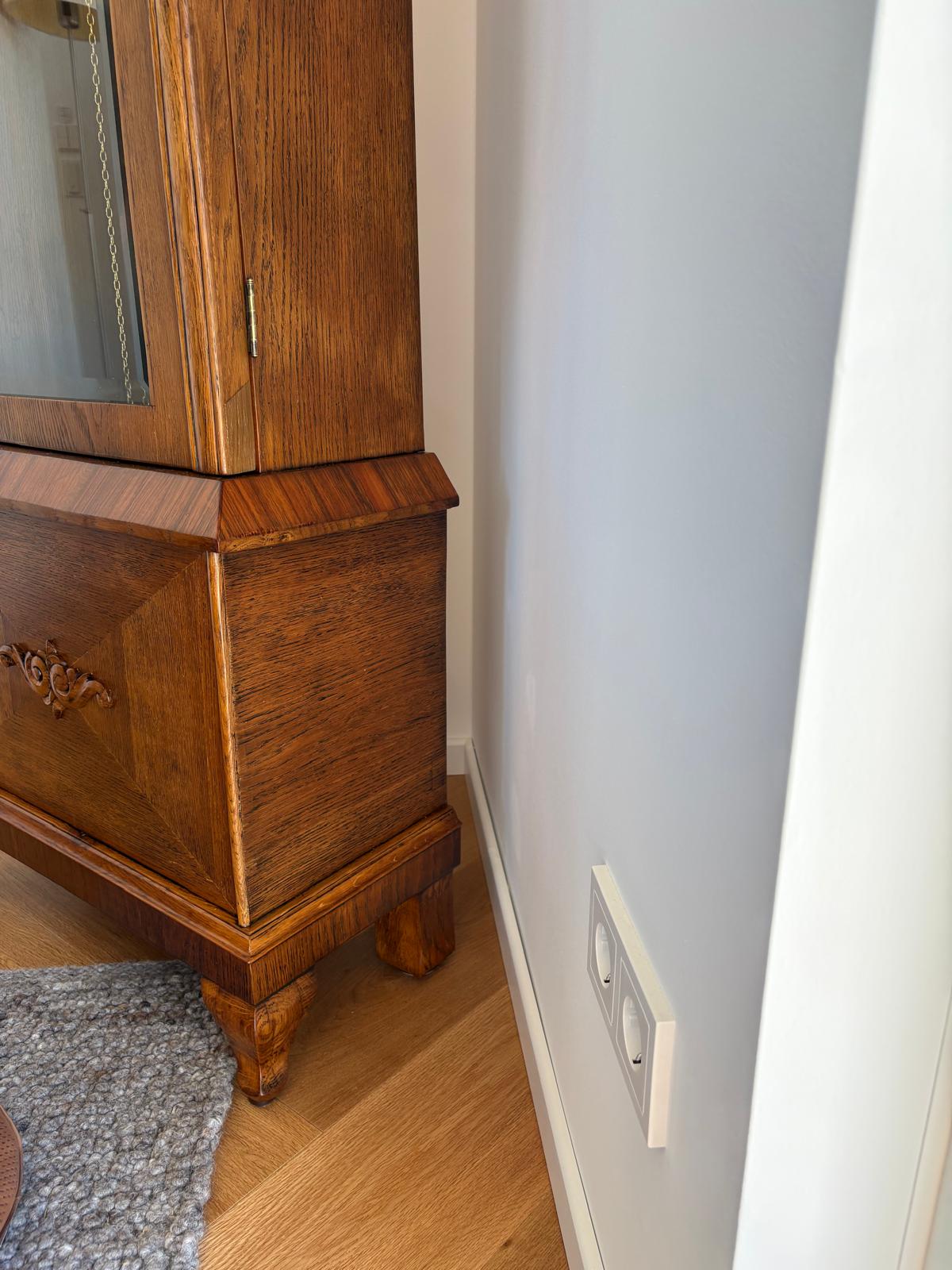 Nahaufnahme des fertig restaurierten unteren Standuhr-Gehäuses mit Sockel, Furnierflächen und stabilen Füßen.